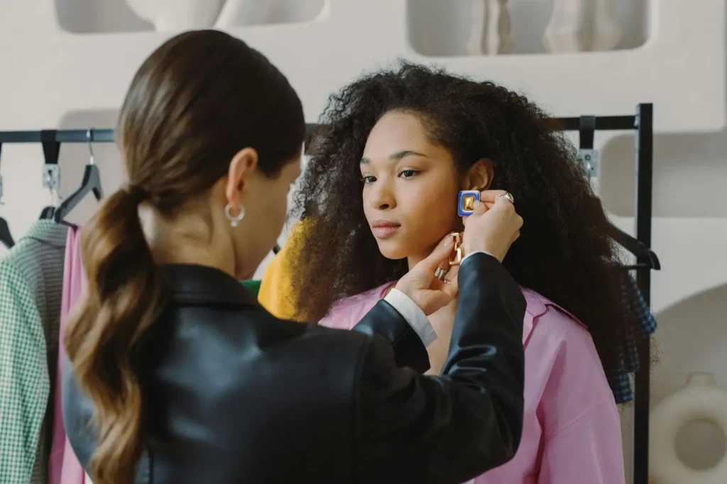 A stylist holds up an accessory option to her client to decide what looks best.