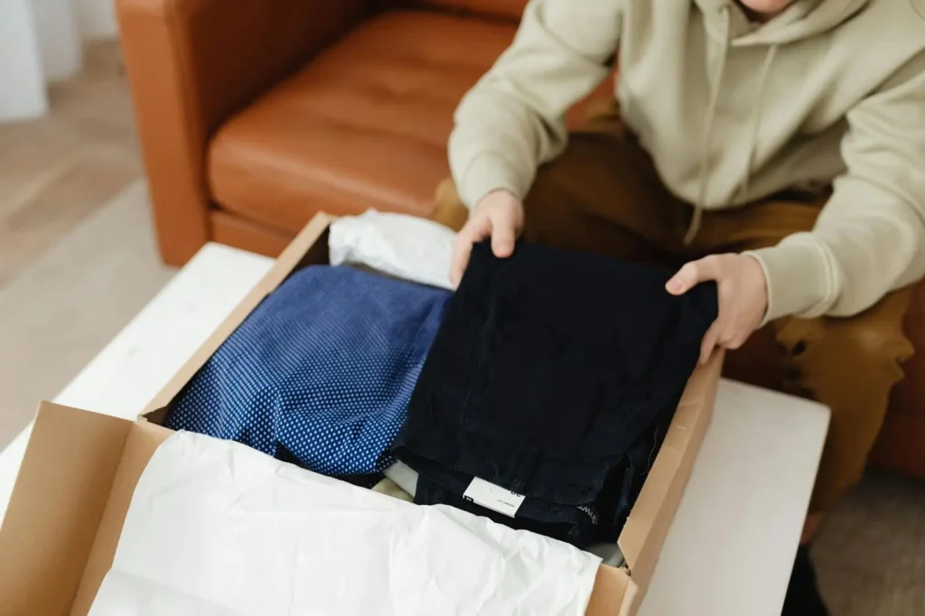 An individual opens a subscription box filled with clothes from a fashion subscription service.
