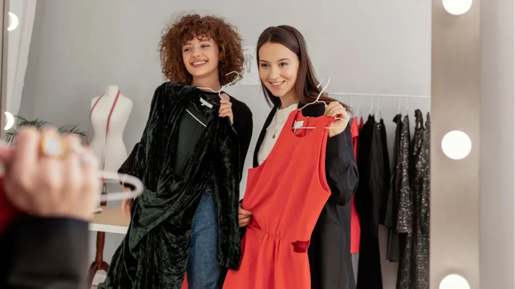 Two young shoppers model potential outfits in a mirror. 