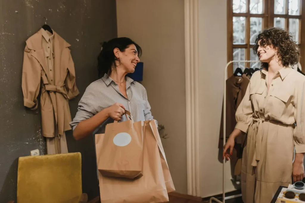 Two women smile and chat in a retail store.